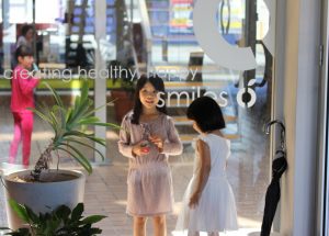 Young girls standing a glass window of Carlingford Dental Surgery